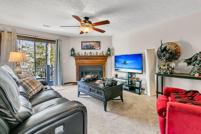 living area featuring light carpet, ceiling fan, visible vents, and a glass covered fireplace