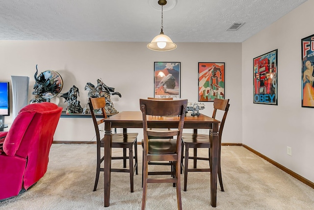 dining room featuring light carpet, baseboards, visible vents, and a textured ceiling