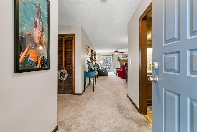 hallway featuring carpet flooring, a textured ceiling, and baseboards