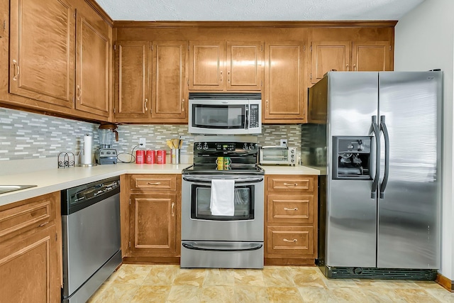 kitchen featuring light countertops, appliances with stainless steel finishes, backsplash, and brown cabinets