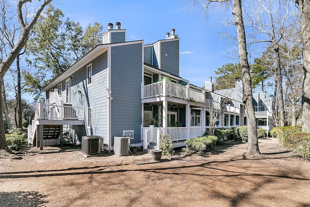 view of side of property with stairway, a chimney, and central AC unit