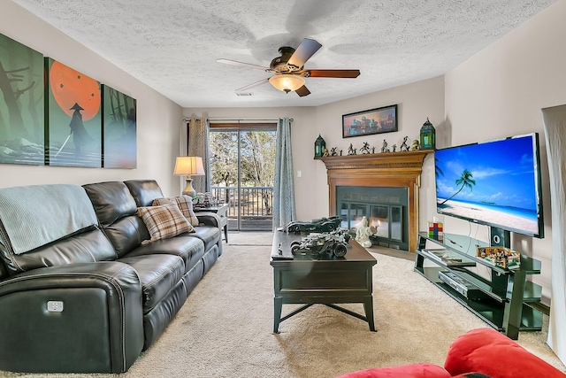 living room featuring a textured ceiling, carpet floors, a fireplace with flush hearth, visible vents, and a ceiling fan