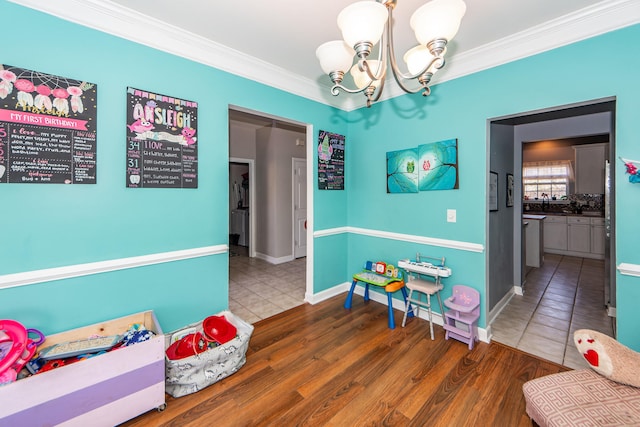 game room with hardwood / wood-style floors, crown molding, and a chandelier