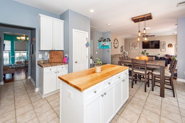 kitchen with white cabinetry, butcher block counters, pendant lighting, a notable chandelier, and a center island