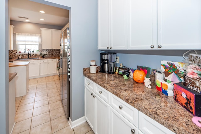 kitchen with sink, white cabinetry, and dark stone counters