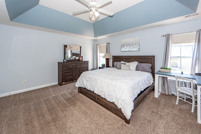 carpeted bedroom with a raised ceiling and ceiling fan