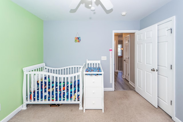 bedroom featuring a closet, ceiling fan, light colored carpet, and a nursery area