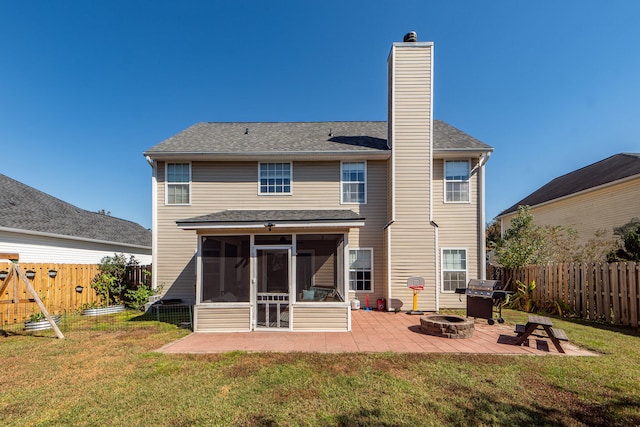 back of house featuring a sunroom, a patio area, an outdoor fire pit, and a yard