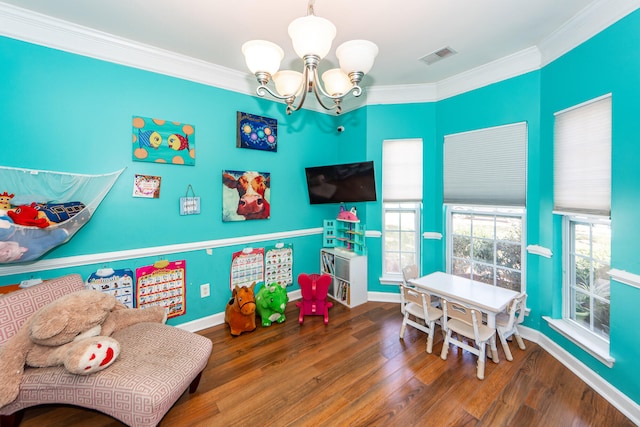 playroom with ornamental molding, a chandelier, and dark hardwood / wood-style floors