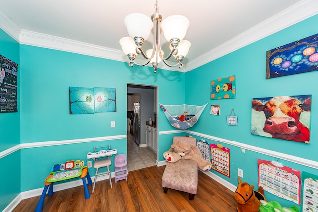 playroom featuring dark wood-type flooring, ornamental molding, and a chandelier