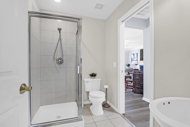 bathroom featuring a shower with shower door, toilet, and tile patterned flooring