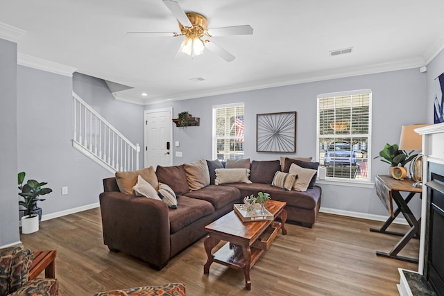 living room featuring ceiling fan, dark hardwood / wood-style flooring, crown molding, and a fireplace