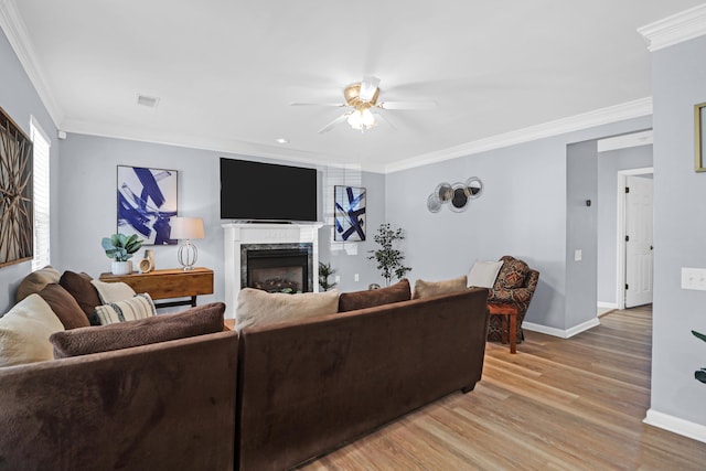 living room with ceiling fan, a high end fireplace, crown molding, and light hardwood / wood-style floors