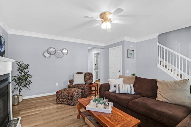 living room with ceiling fan, crown molding, a premium fireplace, and light wood-type flooring