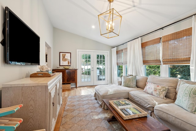 living room featuring french doors, lofted ceiling, light hardwood / wood-style flooring, and a notable chandelier