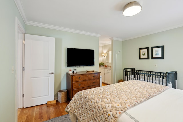 bedroom with crown molding, light hardwood / wood-style floors, and ensuite bathroom