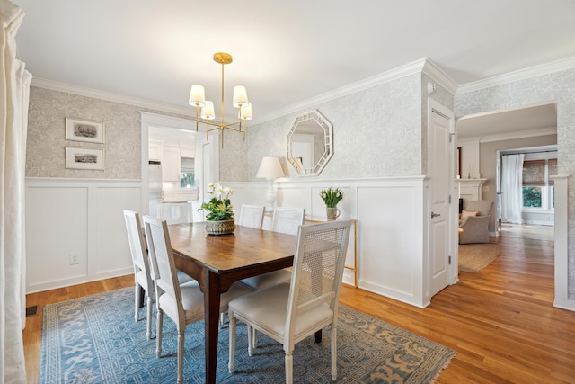 dining room featuring hardwood / wood-style flooring, a wealth of natural light, ornamental molding, and a chandelier