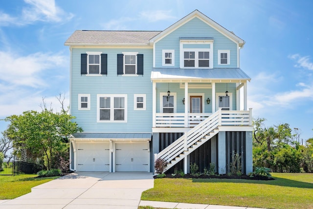 raised beach house featuring an attached garage, a front lawn, covered porch, and concrete driveway