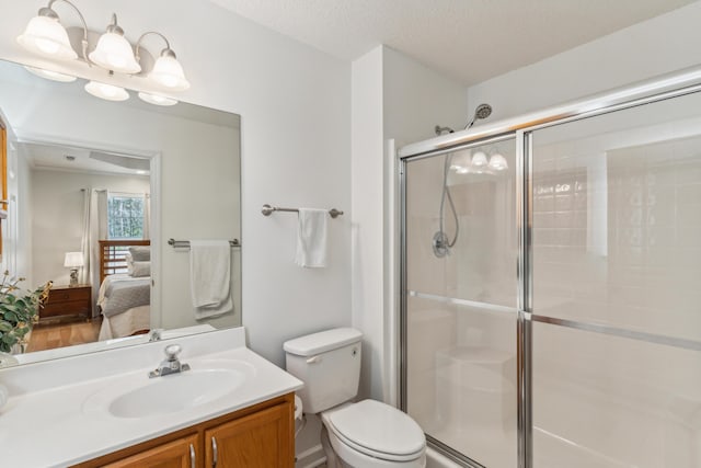 full bath featuring connected bathroom, a shower stall, toilet, vanity, and a textured ceiling