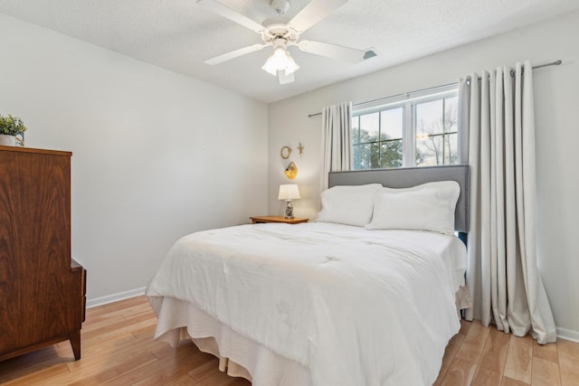 bedroom featuring baseboards, light wood-style floors, and a textured ceiling