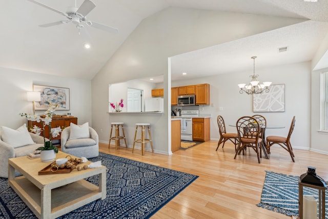 living area with visible vents, high vaulted ceiling, ceiling fan with notable chandelier, light wood finished floors, and baseboards