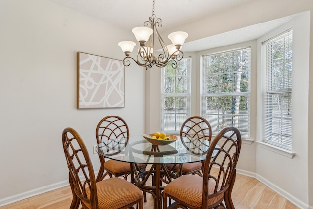 dining space with baseboards, an inviting chandelier, and light wood-style flooring