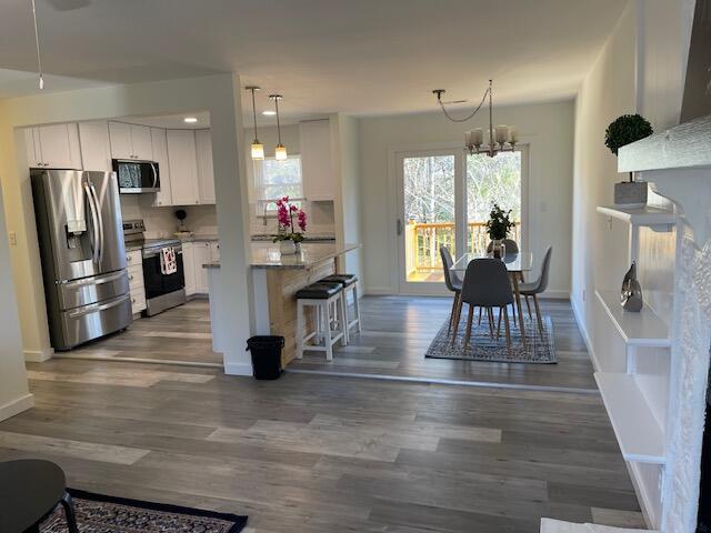 kitchen with decorative light fixtures, white cabinetry, stainless steel appliances, and a notable chandelier