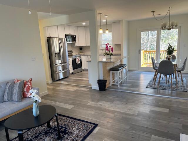 kitchen featuring light stone counters, white cabinetry, appliances with stainless steel finishes, and a chandelier