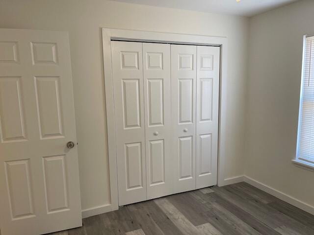 unfurnished bedroom featuring a closet and dark hardwood / wood-style flooring