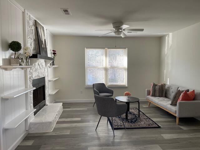 living room featuring ceiling fan, dark wood-type flooring, and a fireplace