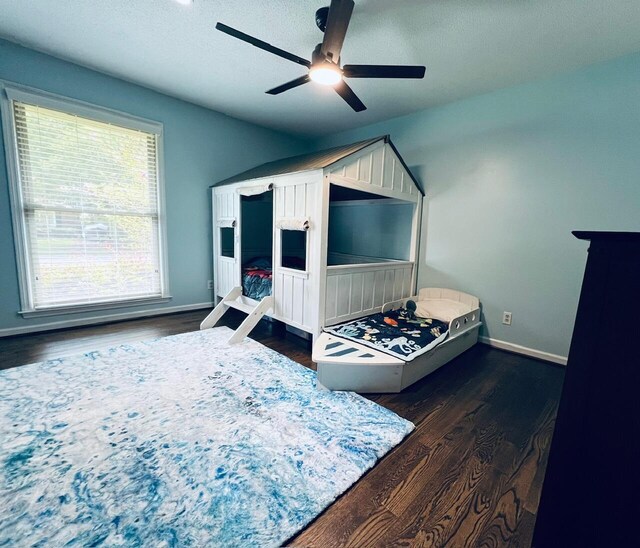 bedroom with dark wood-type flooring, ceiling fan, and a textured ceiling