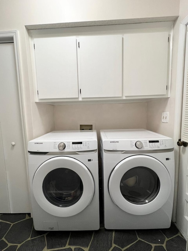 laundry area with dark tile patterned floors, cabinets, and washer and dryer