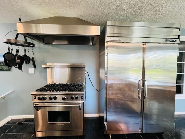 kitchen with dark tile patterned floors, exhaust hood, high end appliances, and a textured ceiling