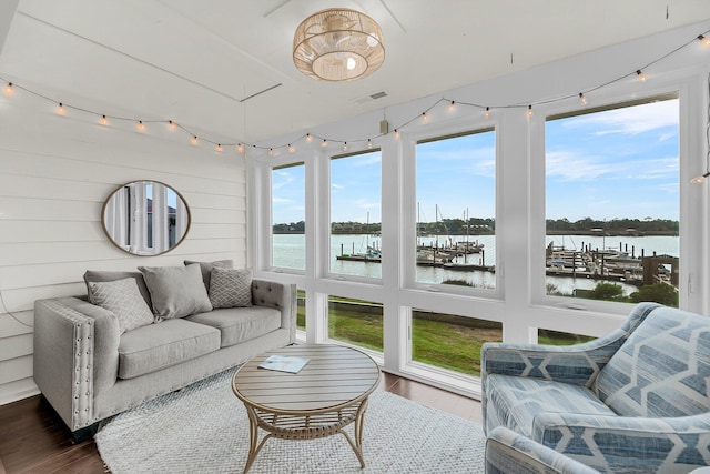 sunroom with wood finished floors, a water view, and wood walls