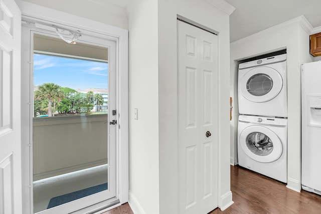 clothes washing area featuring estacked washer and dryer, crown molding, wood finished floors, and baseboards