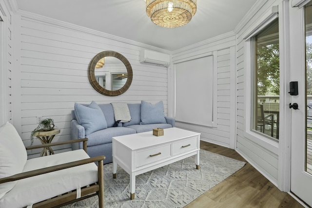 living area featuring an AC wall unit, crown molding, wooden walls, and wood finished floors