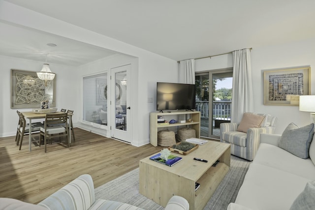 living area with baseboards, light wood finished floors, and an inviting chandelier