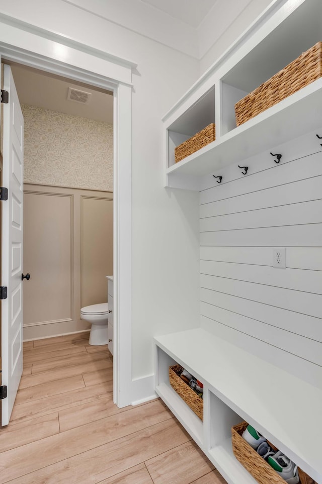 mudroom featuring a decorative wall, visible vents, and light wood-type flooring