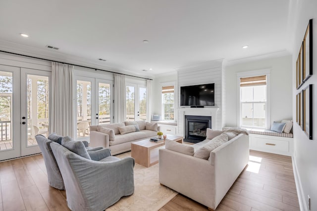 living area featuring visible vents, french doors, a large fireplace, and light wood-style floors