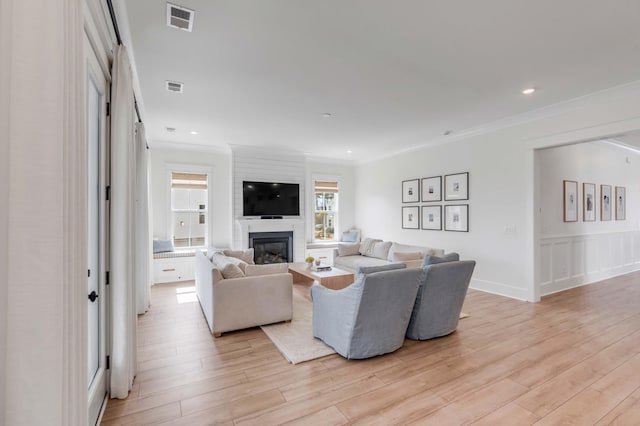 living room featuring visible vents, light wood-style flooring, and ornamental molding