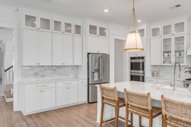 kitchen featuring white cabinets, stainless steel appliances, light countertops, and a sink