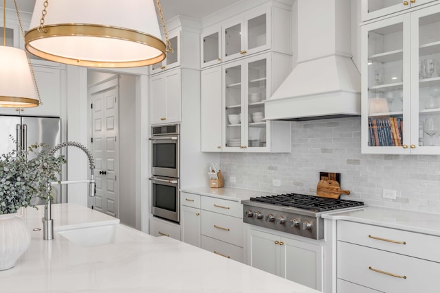 kitchen featuring tasteful backsplash, a sink, appliances with stainless steel finishes, and premium range hood