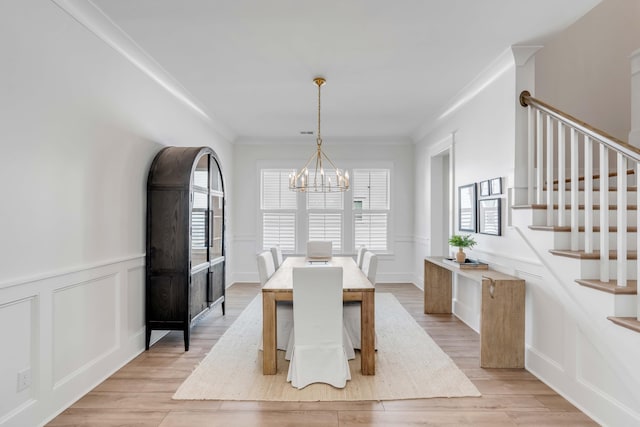 dining room featuring plenty of natural light, an inviting chandelier, ornamental molding, and stairs