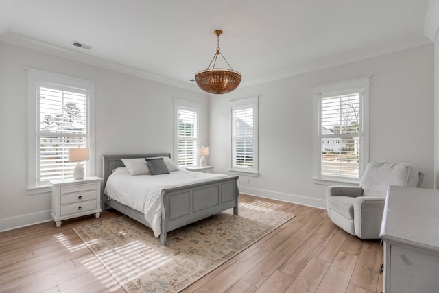 bedroom featuring light wood finished floors, visible vents, crown molding, and baseboards