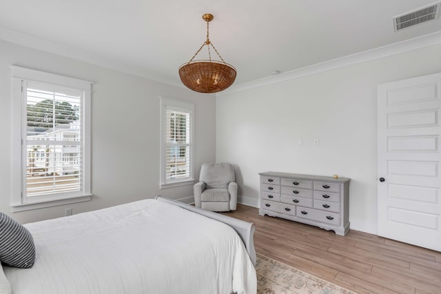 bedroom with light wood-style flooring, baseboards, visible vents, and ornamental molding