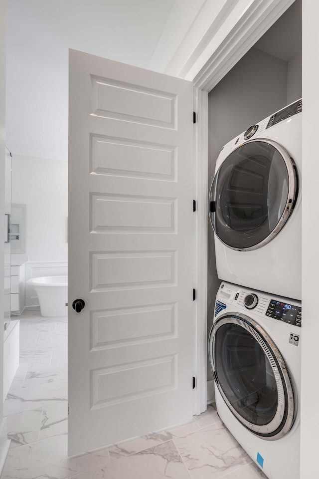 laundry room featuring laundry area, marble finish floor, and stacked washing maching and dryer