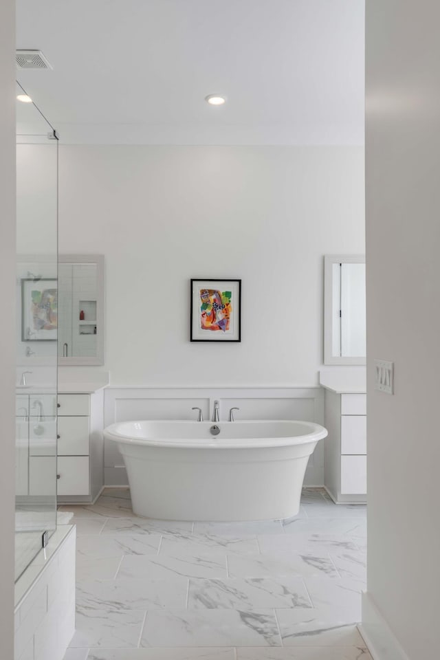 full bathroom featuring vanity, a soaking tub, a wainscoted wall, and marble finish floor