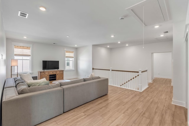 living room with visible vents, baseboards, attic access, light wood-style flooring, and recessed lighting