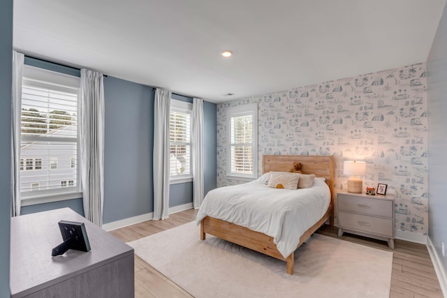 bedroom with wallpapered walls, light wood-type flooring, and baseboards