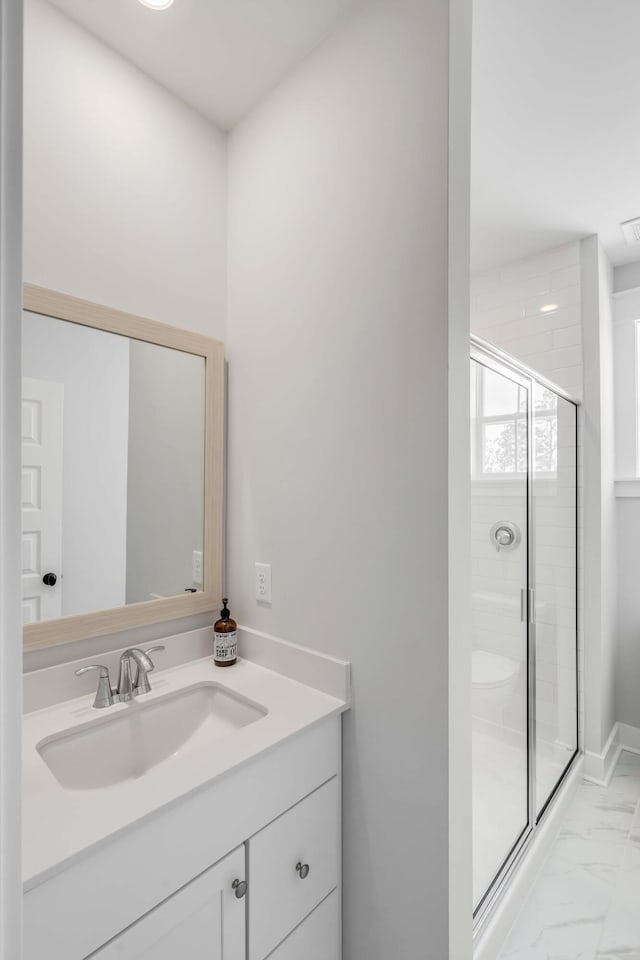 bathroom featuring marble finish floor, vanity, a shower stall, and baseboards